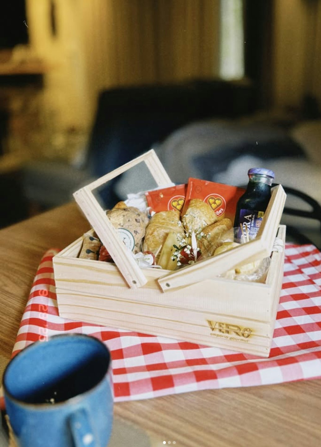 Pastries and juice in a wooden basket on a checkered cloth.