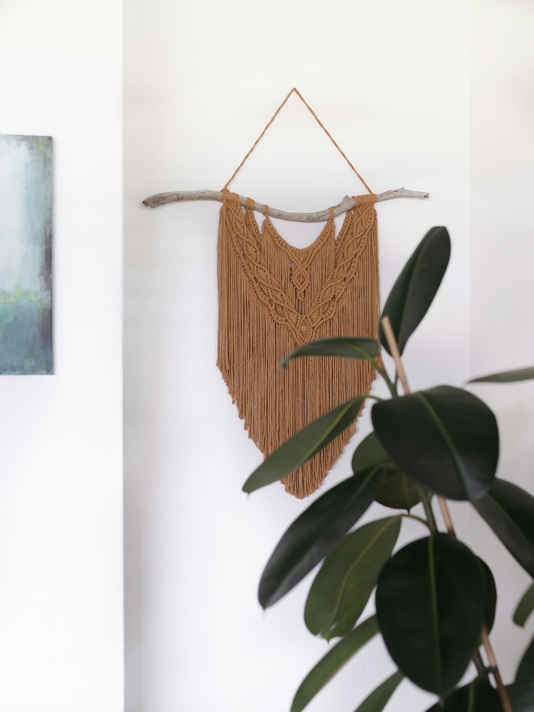 Macrame wall hanging on driftwood against white wall.