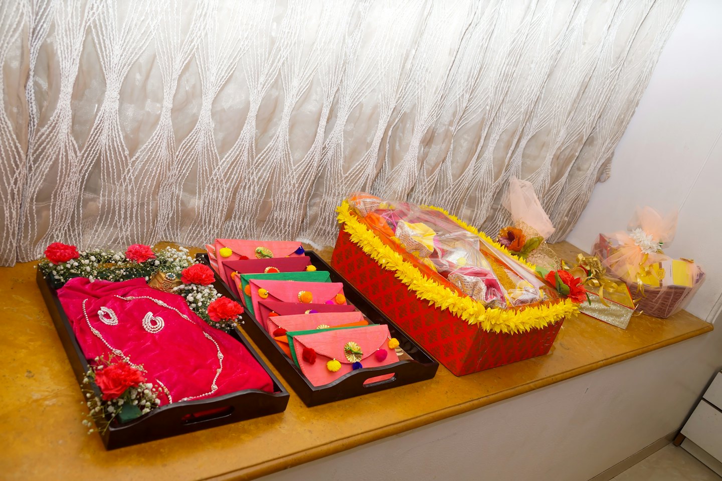 Decorative gift trays and baskets filled with presents on a wooden table.