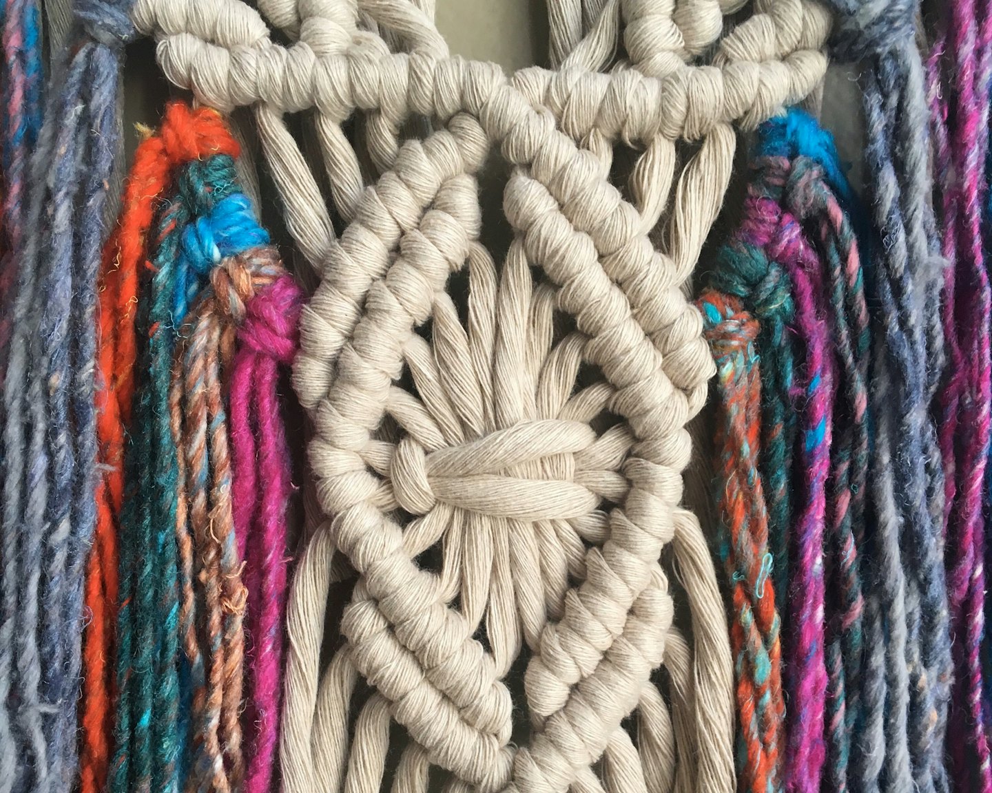 Handmade macrame wall hanging with colorful yarn tassels.